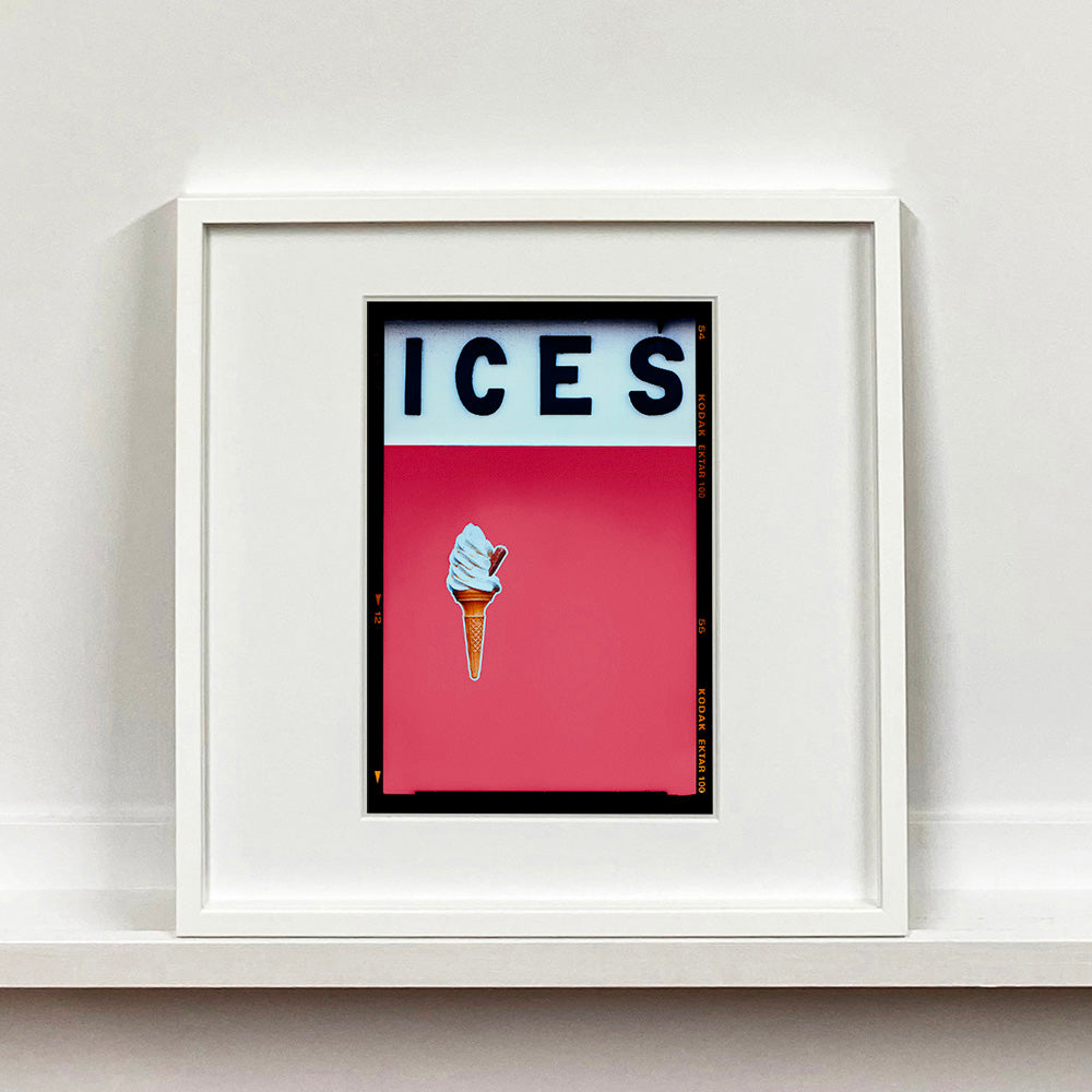 White framed photograph by Richard Heeps.  At the top black letters spell out ICES and below is depicted a 99 icecream cone sitting left of centre against a coral coloured background.  