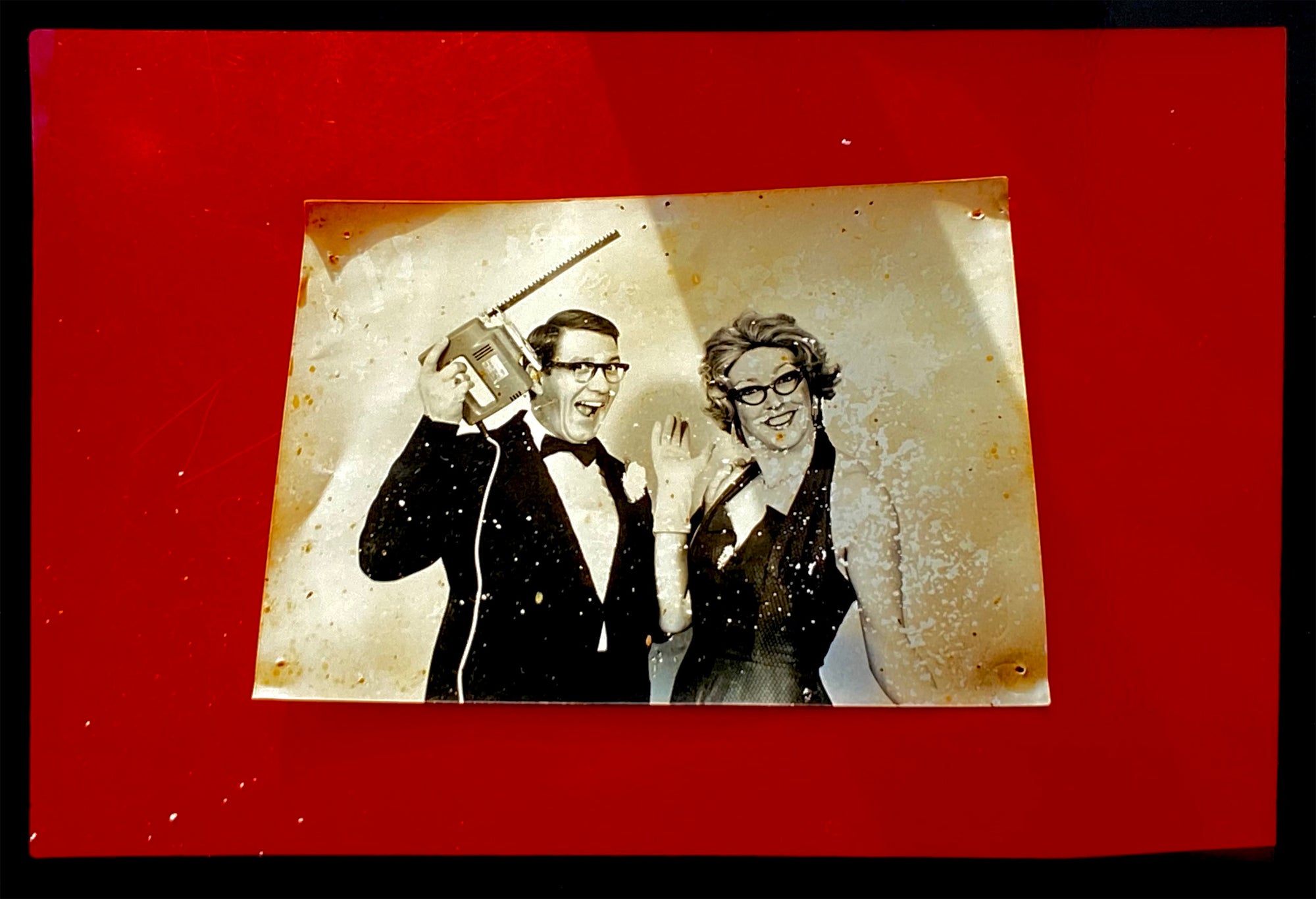'Magic Act' is a sepia toned vintage image laid on a bright red backdrop. This photograph was captured at the Red Lodge, a stop often used by performers as they traveled across the country.