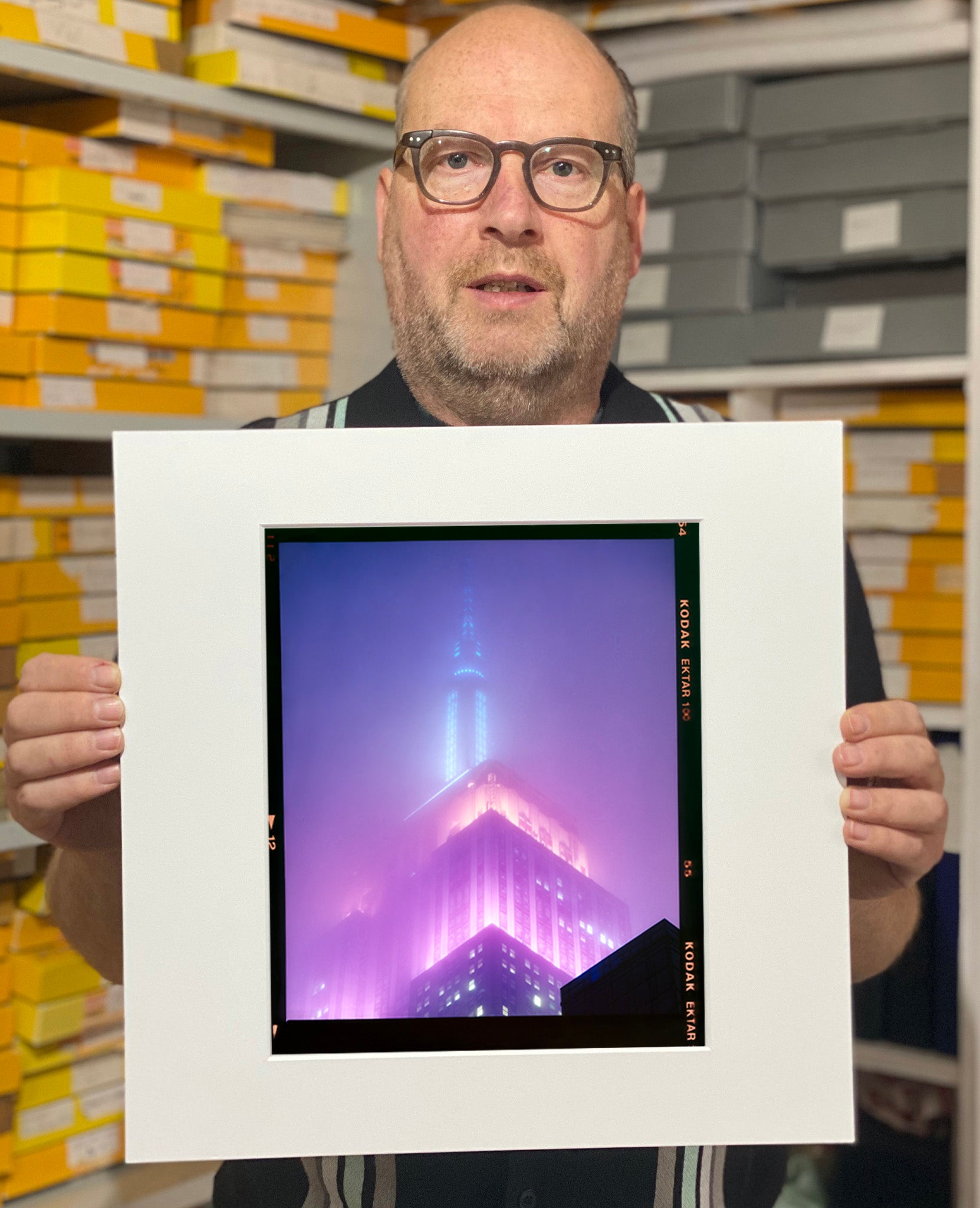 'NOMAD VIII (Film Rebate)', New York. Richard Heeps has photographed the iconic Empire State building in the mist. The NOMAD sequence of photographs capture the art deco architecture illuminated by changing colours, and is part of Richard's street photography portfolio which depict the colour, fabric and structure of cities with distinct style. This 6x7 format edition is bordered by the Kodak film rebate. 