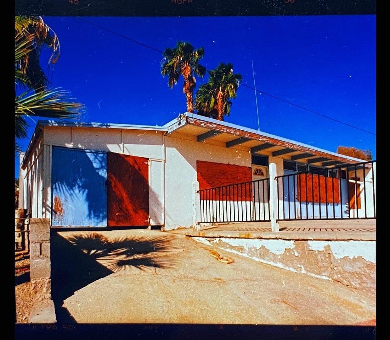 Drive up to an American Motel in California with blue sky and palm trees.