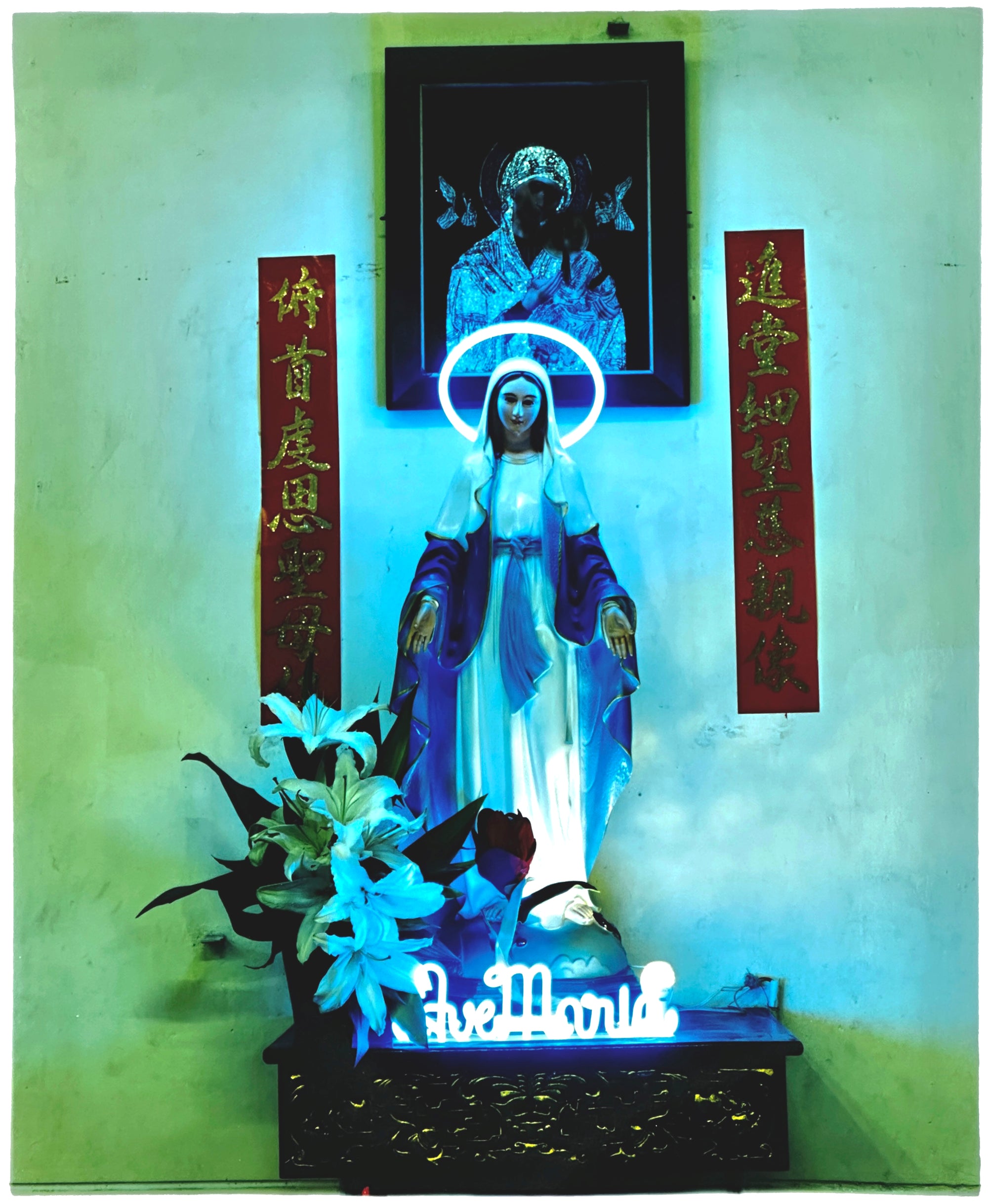 Photograph by Richard Heeps. Ave Maria, with a neon halo and name 'Ave Maria' at her feet. The neon tones the photo in green and blue.