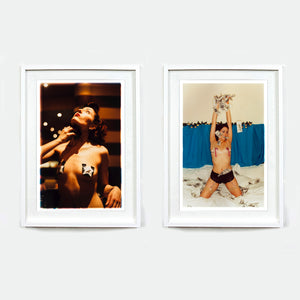 Two white framed burlesque photographic prints by Richard Heeps hanging side by side on a light gray wall. 
