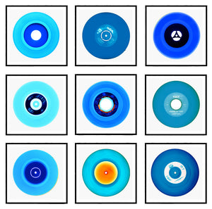 Photograph by Heidler and Heeps. A selection of 9 blue vinyl disks, set in white mounts, with black frames. Set in a 3x3 square.