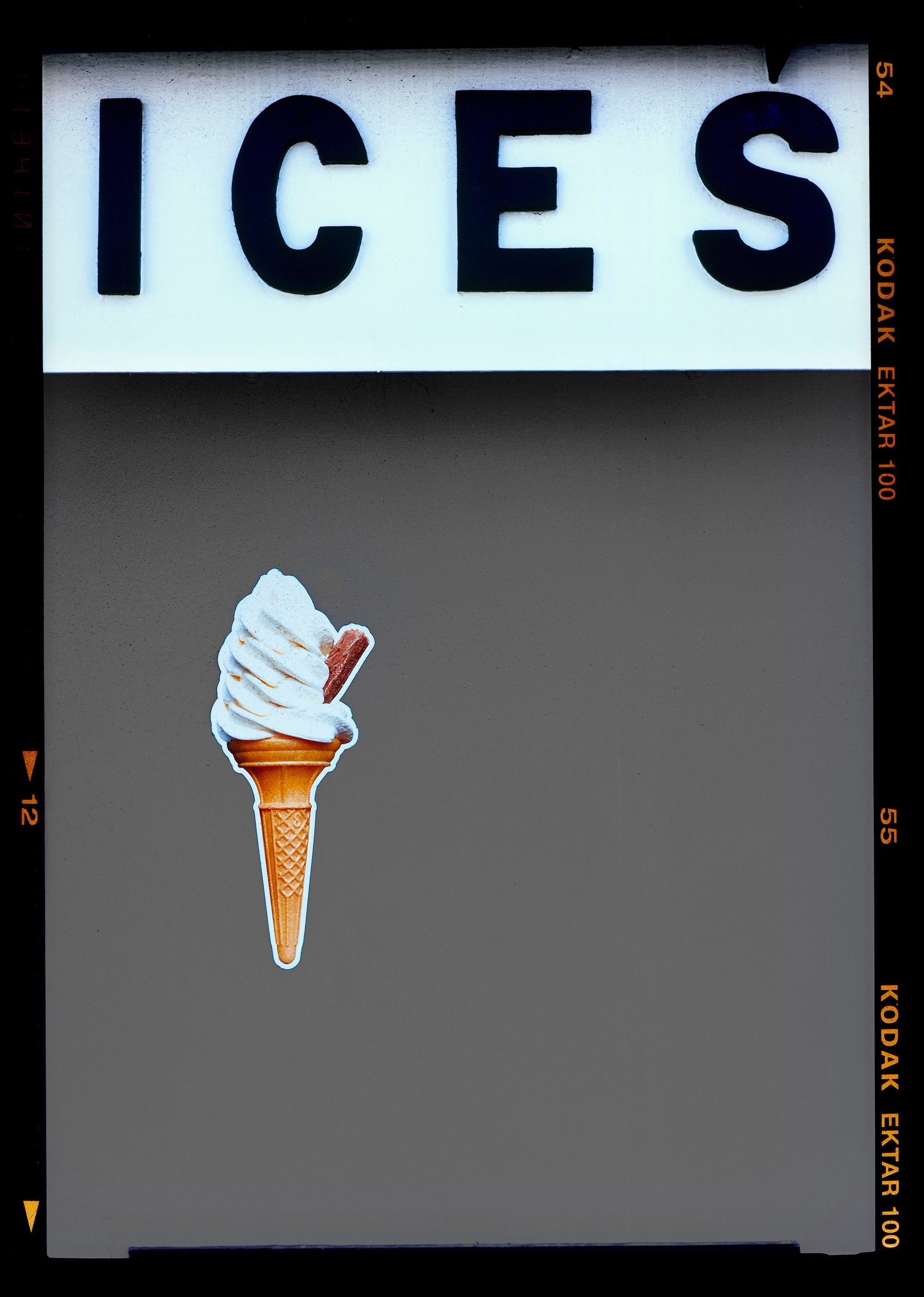 Photograph by Richard Heeps.  At the top black letters spell out ICES and below is depicted a 99 icecream cone sitting left of centre against a grey coloured background.  