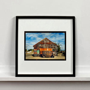 Model T and Garage American road trip colour Kodak Film photograph by Richard Heeps mounted square framed in black