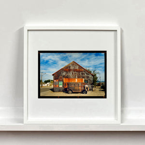 Model T and Garage American road trip colour Kodak Film photograph by Richard Heeps mounted square framed in white.