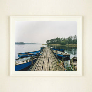 Ormesby Little Broad, a docking jetty with small boats stretches out to the Norfolk Broad photograph by Richard Heeps large framed in white.