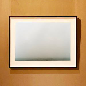 Black framed photograph by Richard Heeps. The photograph is of a wonderfully thick fog and all you can make out is the dark grey of the fenland  along the bottom of the photo.