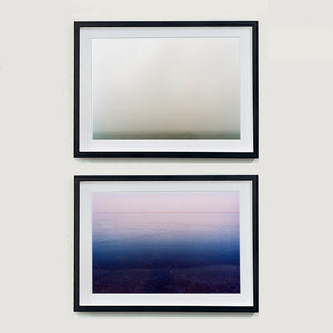 Two Black framed photographs by Richard Heeps. The top photograph is of a wonderfully thick fog and all you can make out is the dark grey of the fenland. The bottom photo shows a light sky at the top shading into a dark blue water at the bottom.