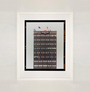 White framed photograph by Richard Heeps. High rise offices with Martini logo on the top facade. 