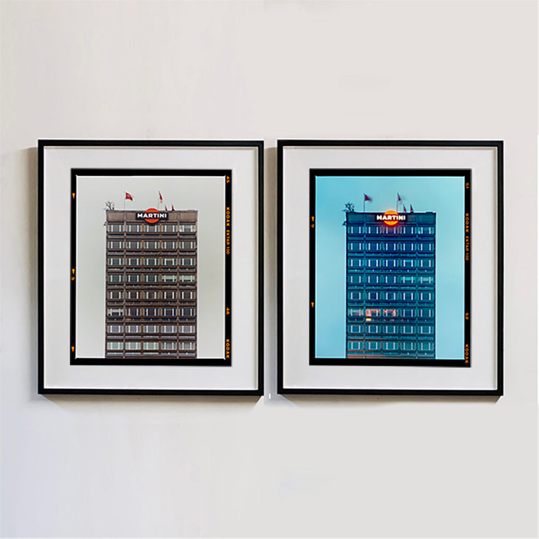 Two black framed photographs by Richard Heeps. Both photos are of a high rise office building with Martini logo on the top facade.  Photographed at different times of day the left hand photograph is in a grey light and the right hand side photo is in a blue light.