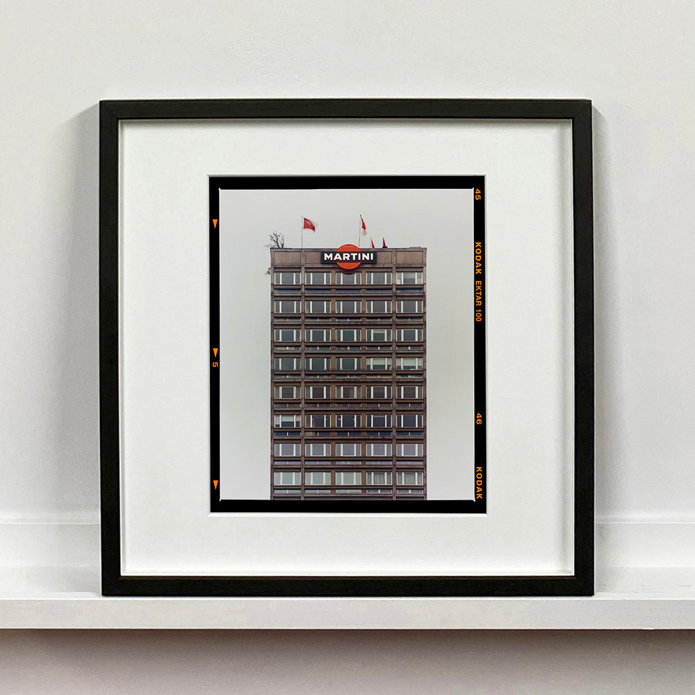 Black framed photograph by Richard Heeps. High rise offices with Martini logo on the top facade. 