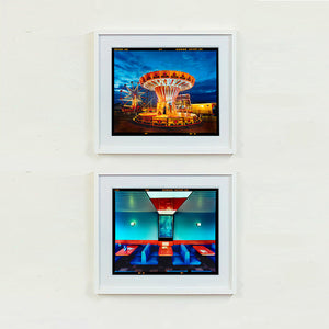 Two white framed photographs by Richard Heeps. The top photograph depicts a fairground ride, the chairoplanes, sits lit in golden and red colours against a dark blue sky. The bottom photograph is of a retro Wimpy in Norfolk. It has a retro diner vibe with dark blue seats and red tables against a blue wall.