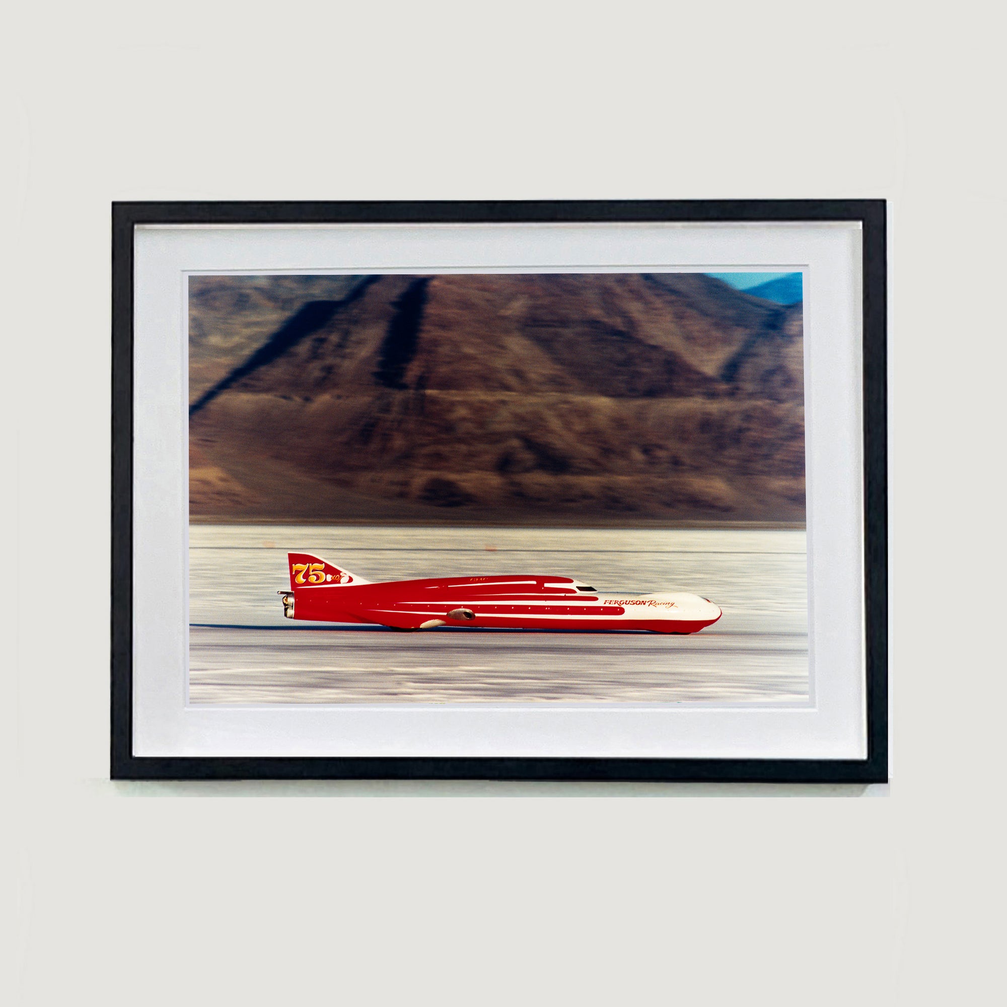 Black framed photograph by Richard Heeps.  A Red Ferguson Racing Streamliner sits on a smooth salt flat with mountains in the background.
