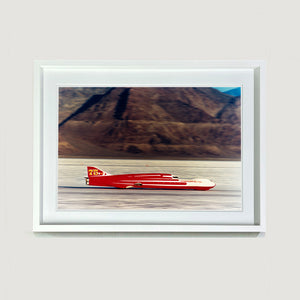 White framed photograph by Richard Heeps.  A Red Ferguson Racing Streamliner sits on a smooth salt flat with mountains in the background.