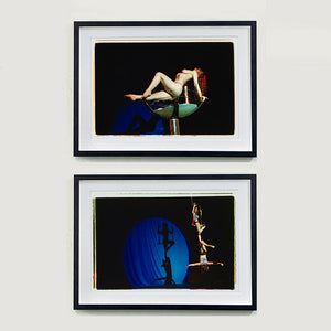 Two black framed photographs by Richard Heeps. The top photograph shows a Burlesque Dancer arches her back while balancing over a human size champagne glass. The bottom photograph show two burlesque dancers together on a trapeze with a blue circle of light at the back showing their shadow.