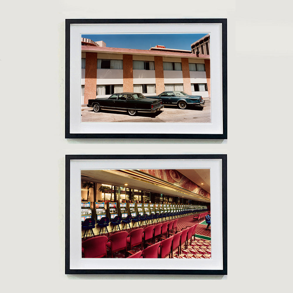 Two black framed photographs by Richard Heeps. Both retro photograph, one  has two classic Lincoln cars parked outside a hotel in Las Vegas. The other is a row of slot machines with a rows of neatly lined stools, taken in a Las Vegas casino.