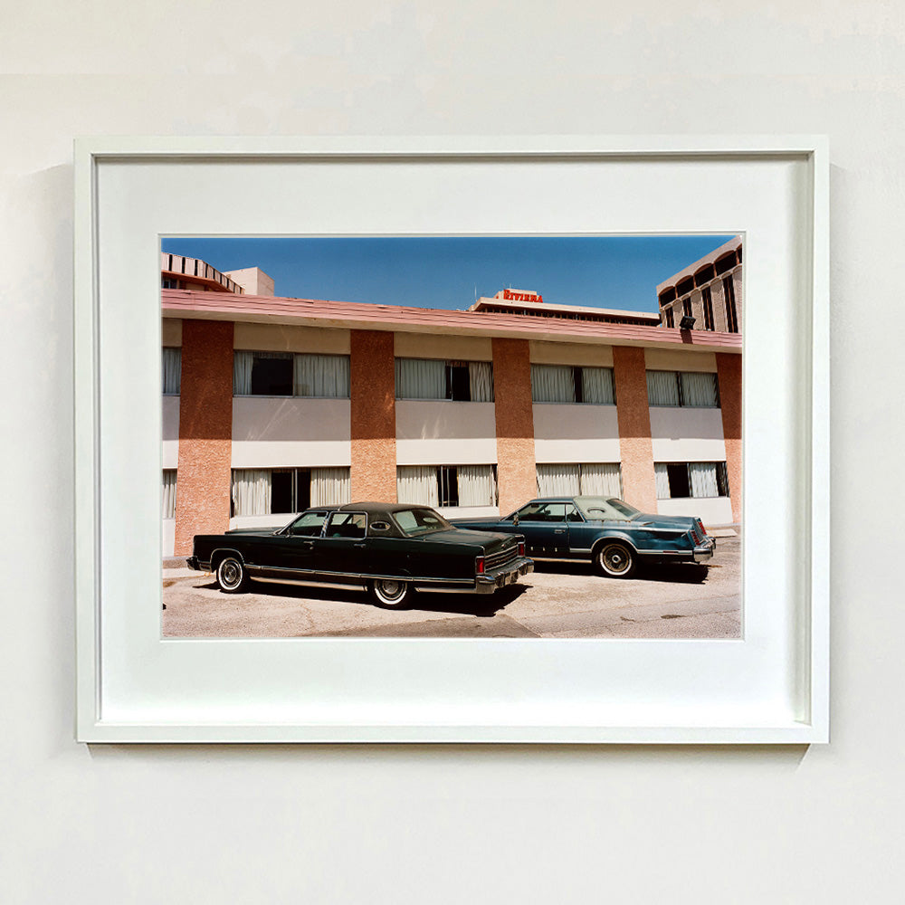 White framed photograph by Richard Heeps. This retro photograph has two classic Lincoln cars parked outside a hotel in Las Vegas. 