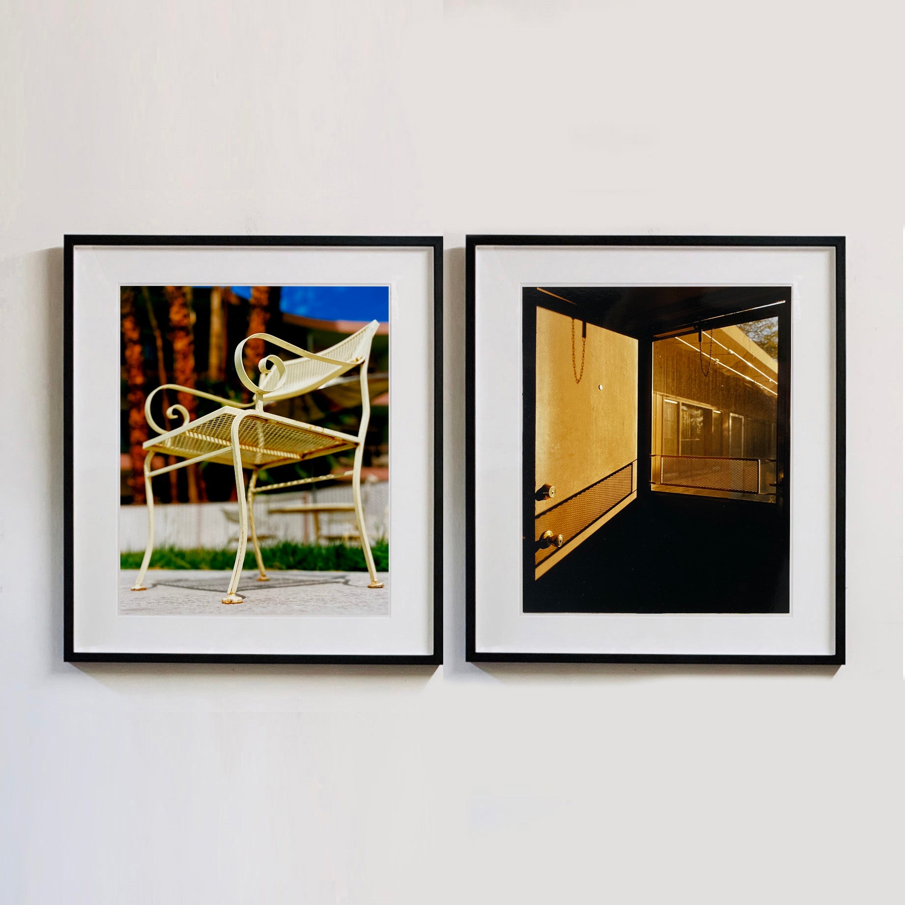 Two black framed photographs by Richard Heeps. The photograph on the left is of a cream chair sitting on hard standing, behind the chair and slightly out of focus is lush green grass and warm red tree trunks. The photograph on the right hand side depicts the evening sun casting a shadow as it glows through a window in a door.