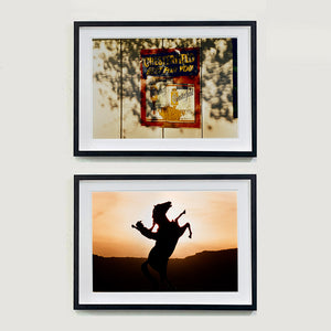 Two framed photographs by Richard Heeps. The top one shows a plastic retro cigarette sign  for Chesterfield cigarettes is stuck to a white wash wooden fence. The words Chesterfield Best for You are raised on the sign and the sign is in a dappled light. The bottom photograph is the silhoette of a bucking cowboy in a sunset with his hand aloft.