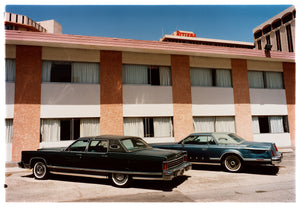 Photograph by Richard Heeps. This retro photograph has two classic Lincoln cars parked outside a hotel in Las Vegas. 