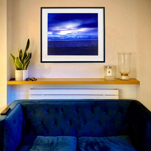 In situ photograph held by photographer Richard Heeps. A blue light hits vast land, mountains and a big sky.