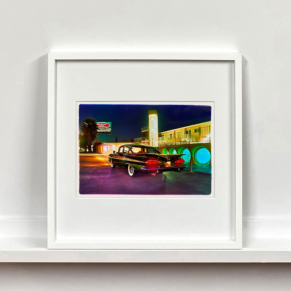 White framed photograph by Richard Heeps. A Chevy Bel Air is central shot and off to the right are the pools and balcony of the Glass Pool Motel, Las Vegas.