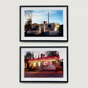 Two black framed photographs by Richard Heeps. The top photograph a vintage American aluminum caravan home surrounded by a white picket fence and at the front a white arch. The bottom photograph depicts a one storey small building "Dot's Diner" brightly lit with a pink roof, with Hamburgers, Hot Dogs, Shakes, Fries written along the top of the building.