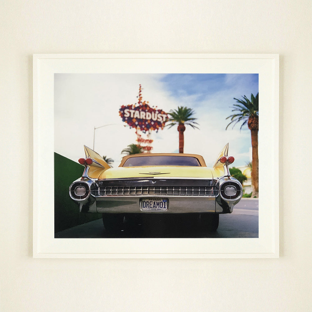 White framed photograph by Richard Heeps.  The back end of the classic American car with a number place DREAM01 sits underneath the STARDUST casino sign.