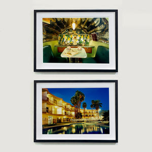 Two black framed photographs by Richard Heeps. The top photograph is inside a trailer, there is a fixed table and chairs with two tea cups and saucers on the table. Behind on the shelf is a tea set and a doll dressed as a bride. The bottom photograph is a hotel and its reflection in the swimming pool taken at night time, lit by the hotel lights.