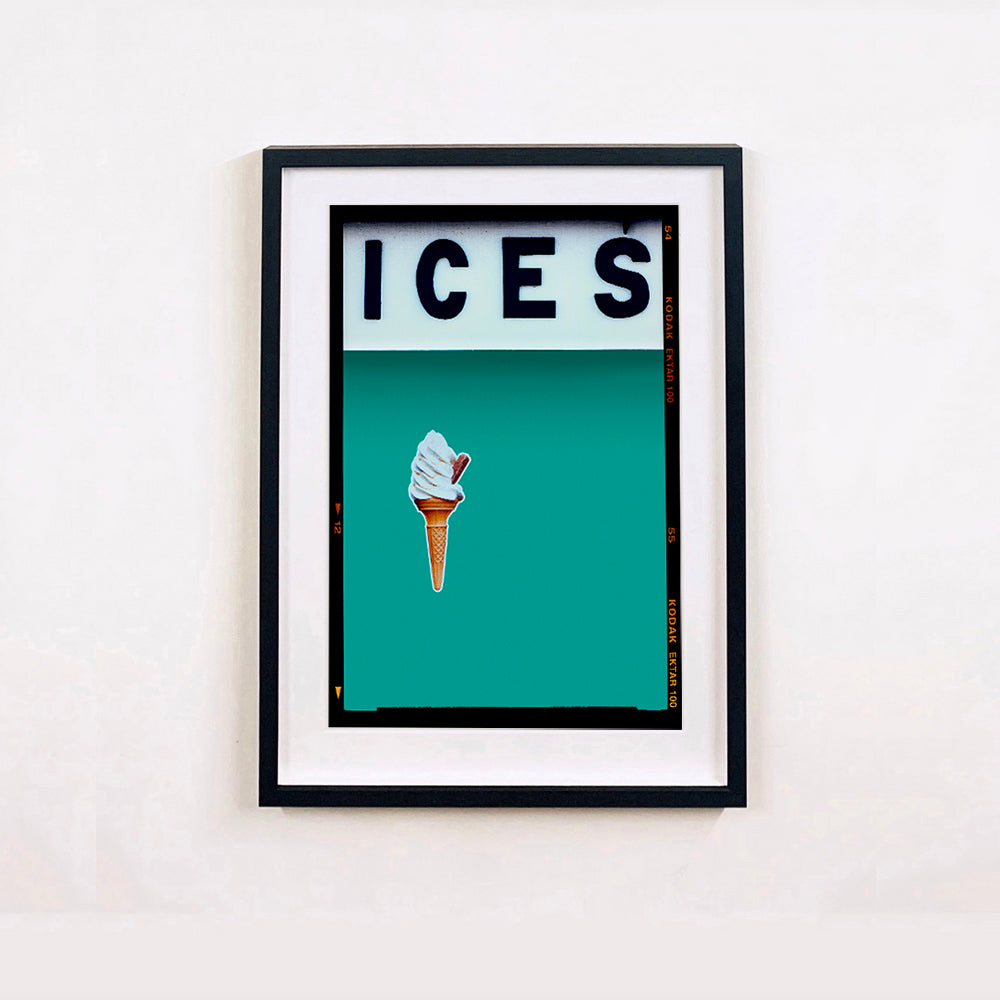 Black framed photograph by Richard Heeps.  At the top black letters spell out ICES and below is depicted a 99 icecream cone sitting left of centre against a Turquoise Teal coloured background.  