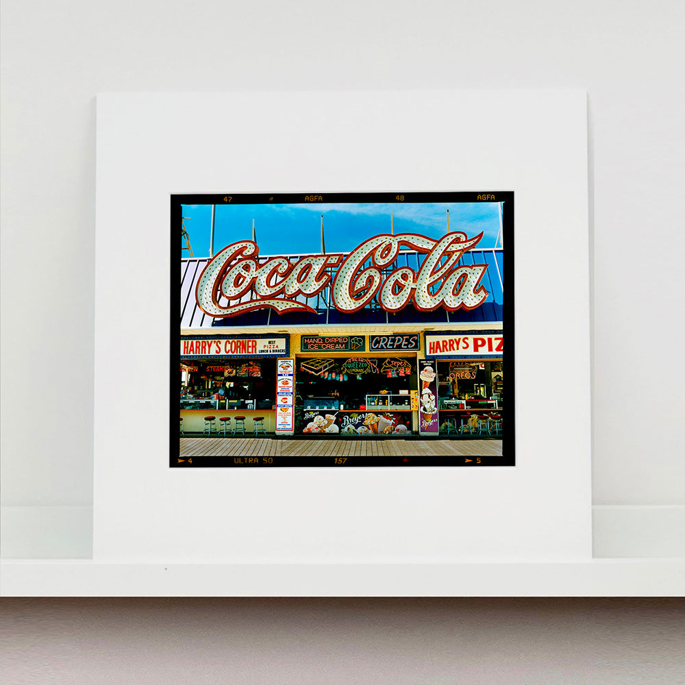 Mounted photograph by Richard Heeps. Harry's Corner was taken on the wildwood boardwalk, featuring neon typography and the iconic Coca-Cola sign against a bright blue sky. 