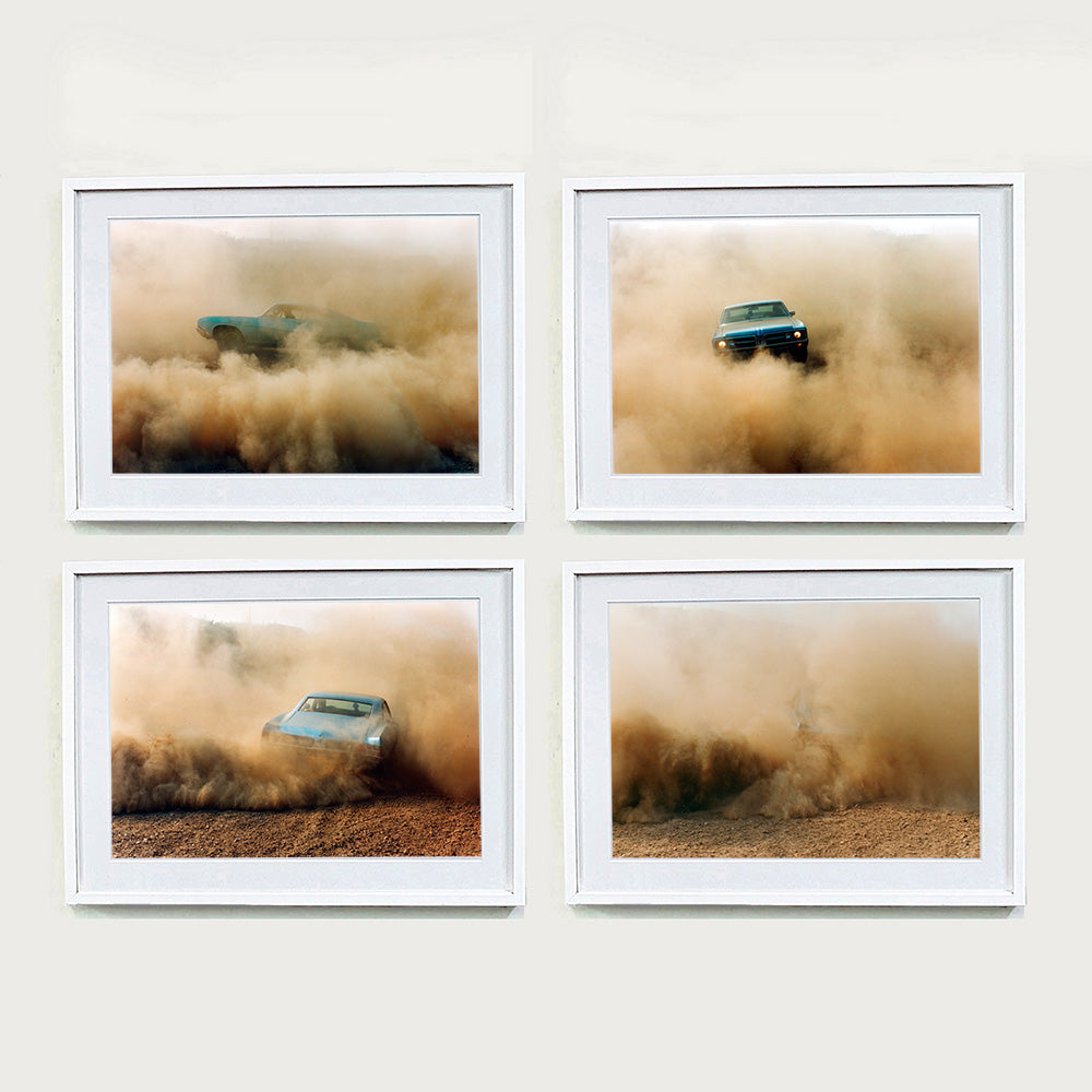 Four white framed photographs by Richard Heeps. The four photographs are of a light blue Buick car moving and slightly obscured by the dust clouds which it has created. The car is sideways on in the first photograph, coming towards the camera in the second, heading away in the third and can hardly be seen in the fourth photograph.