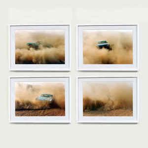 Four white framed photographs by Richard Heeps. The four photographs are of a light blue Buick car moving and slightly obscured by the dust clouds which it has created. The car is sideways on in the first photograph, head on in the second, its back in the third and can hardly been seen in the fourth photograph.