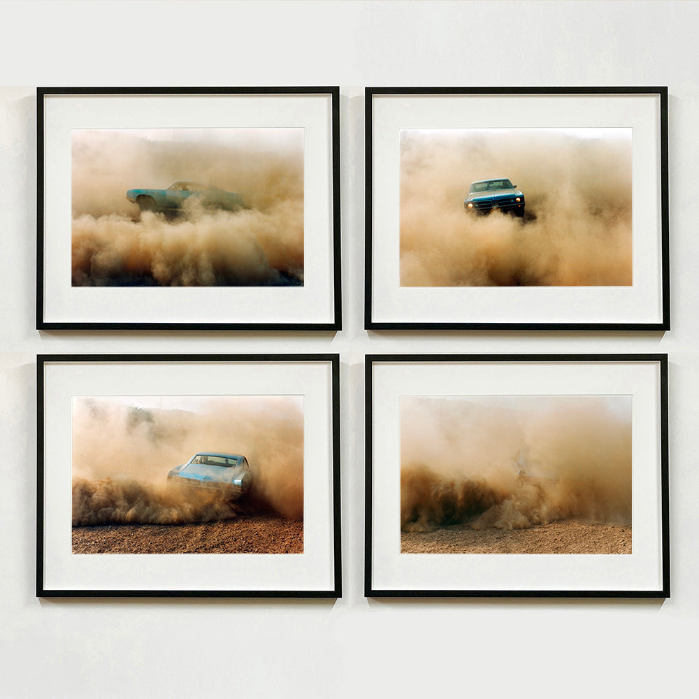 Four Black framed photographs by Richard Heeps. The four photographs are of a light blue Buick car moving and slightly obscured by the dust clouds which it has created. The car is sideways on in the first photograph, head on in the second, its back in the third and can hardly been seen in the fourth photograph.