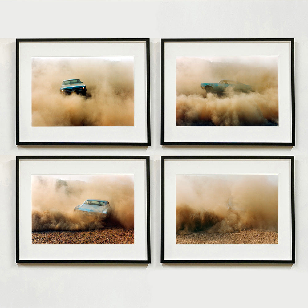 Four black framed photographs by Richard Heeps. The four photographs are of a light blue Buick car moving and slightly obscured by the dust clouds which it has created. The car is sideways on in the first photograph, sideways in the second photograph, head on in the third and can hardly be seen in the fourth photograph.