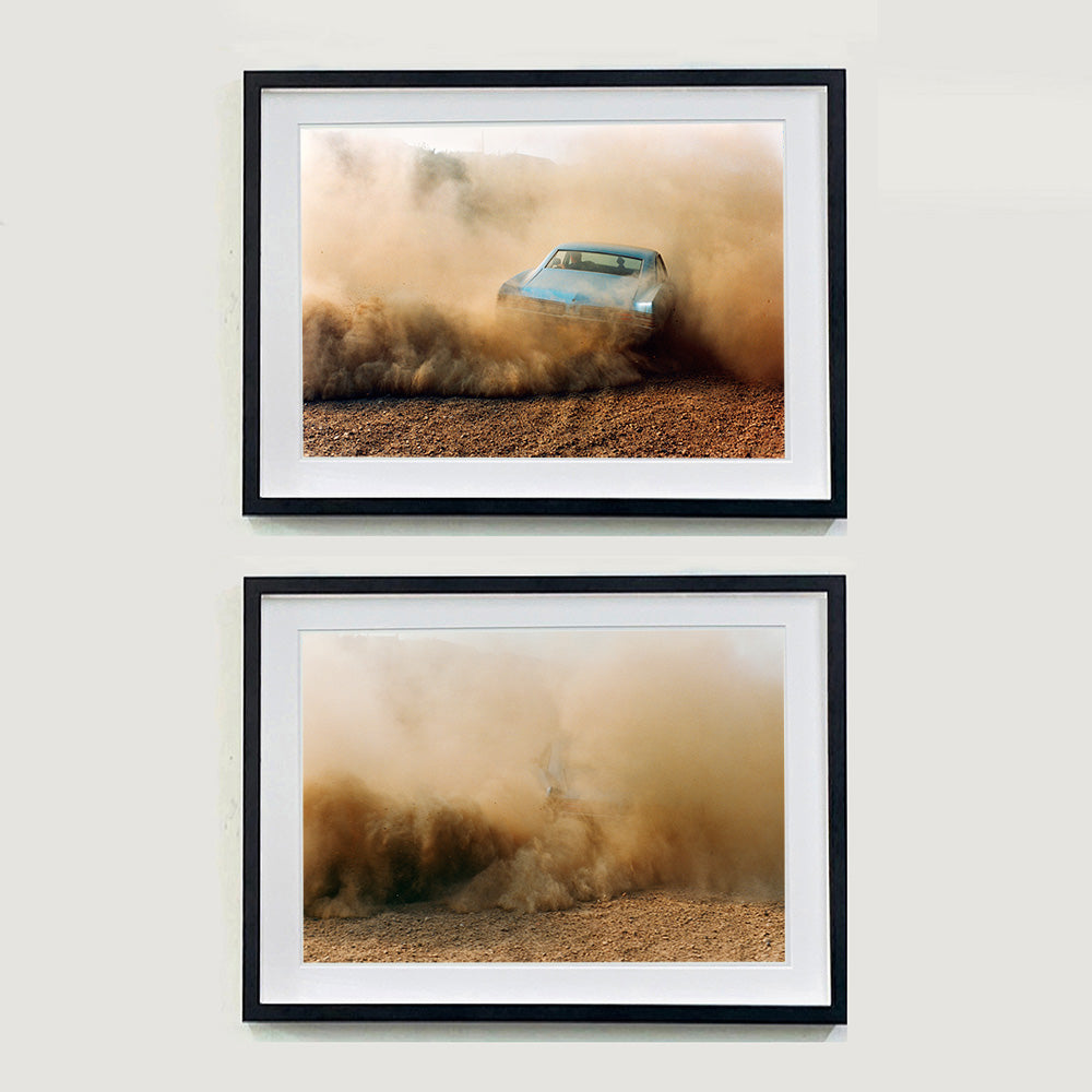 Two black framed photographs by Richard Heeps. The top photograph shows the back view of a light blue Buick car moving and slightly obscured by the dust clouds which it has created, the bottom photograph follows on from the first the cloud of dust is so intense the car is just a vague outline.