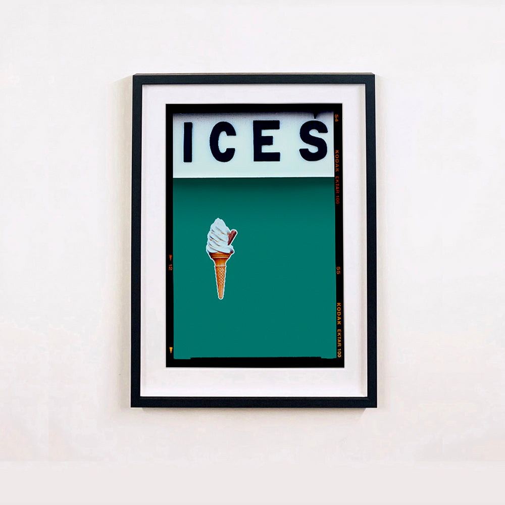 Black framed photograph by Richard Heeps.  At the top black letters spell out ICES and below is depicted a 99 icecream cone sitting left of centre against a deep green teal coloured background.  