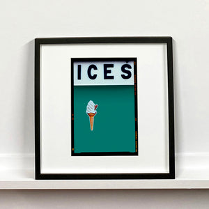 Black framed photograph by Richard Heeps.  At the top black letters spell out ICES and below is depicted a 99 icecream cone sitting left of centre against a deep green teal coloured background.  