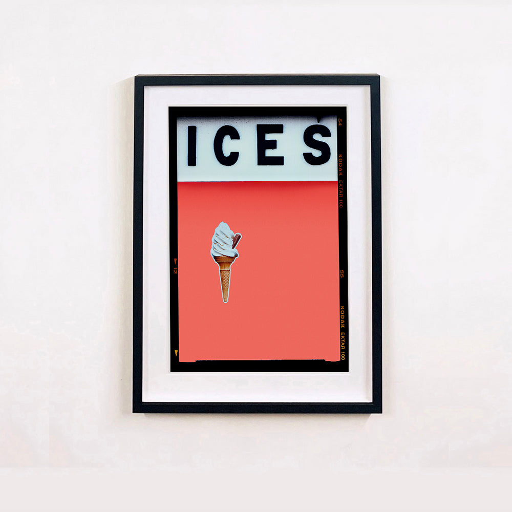 Black framed photograph by Richard Heeps.  At the top black letters spell out ICES and below is depicted a 99 icecream cone sitting left of centre against a melondrama red orange coloured background.  
