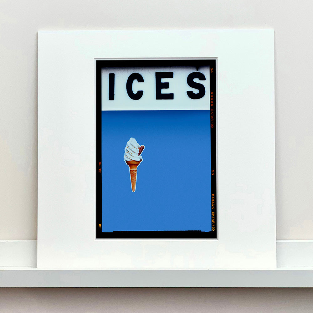 Photograph by Richard Heeps.  At the top black letters spell out ICES and below is depicted a 99 icecream cone sitting left of centre against a Baby Blue coloured background.  