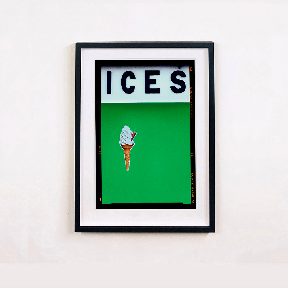 Black framed photograph by Richard Heeps.  At the top black letters spell out ICES and below is depicted a 99 icecream cone sitting left of centre against a green coloured background.  