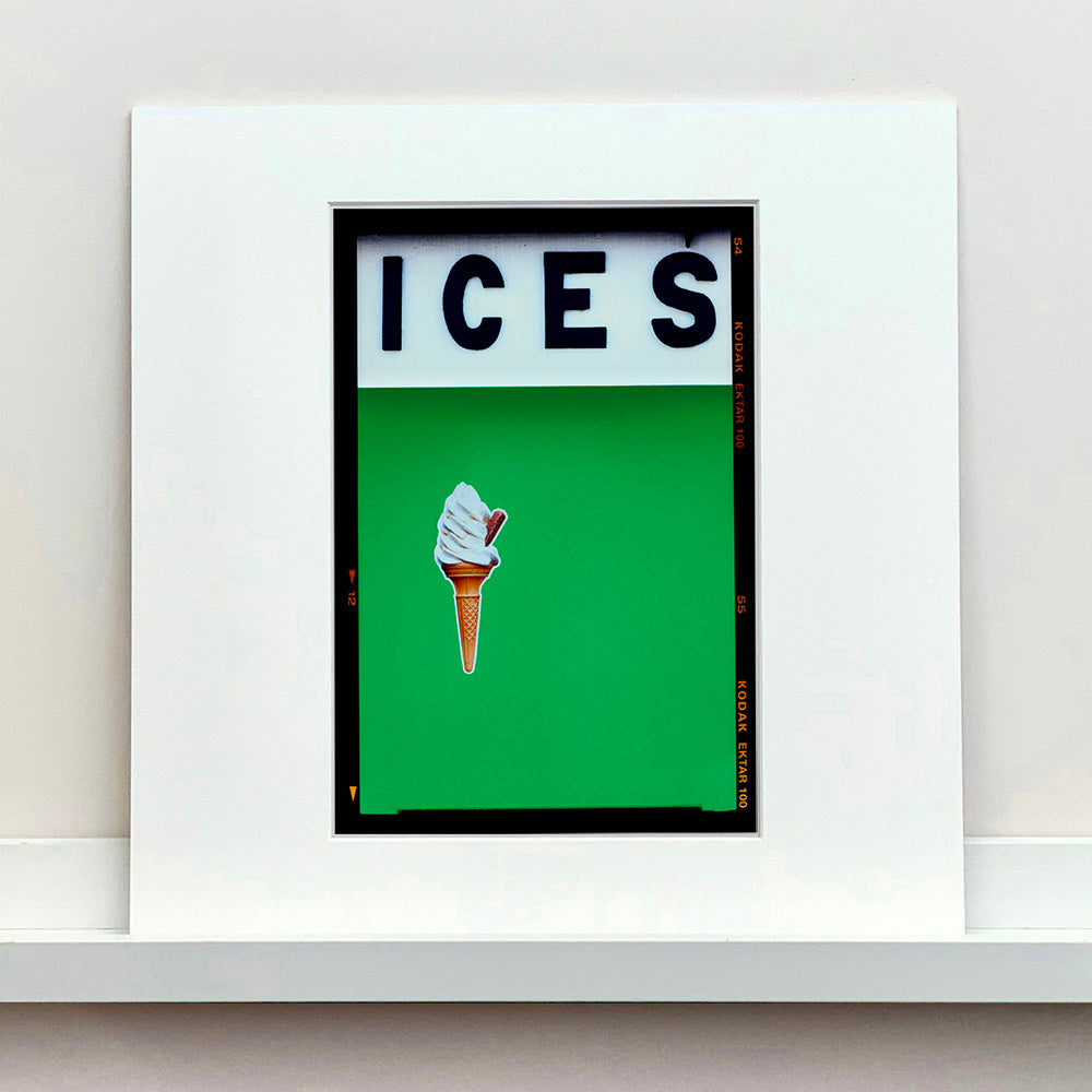 Mounted photograph by Richard Heeps.  At the top black letters spell out ICES and below is depicted a 99 icecream cone sitting left of centre against a green coloured background.  