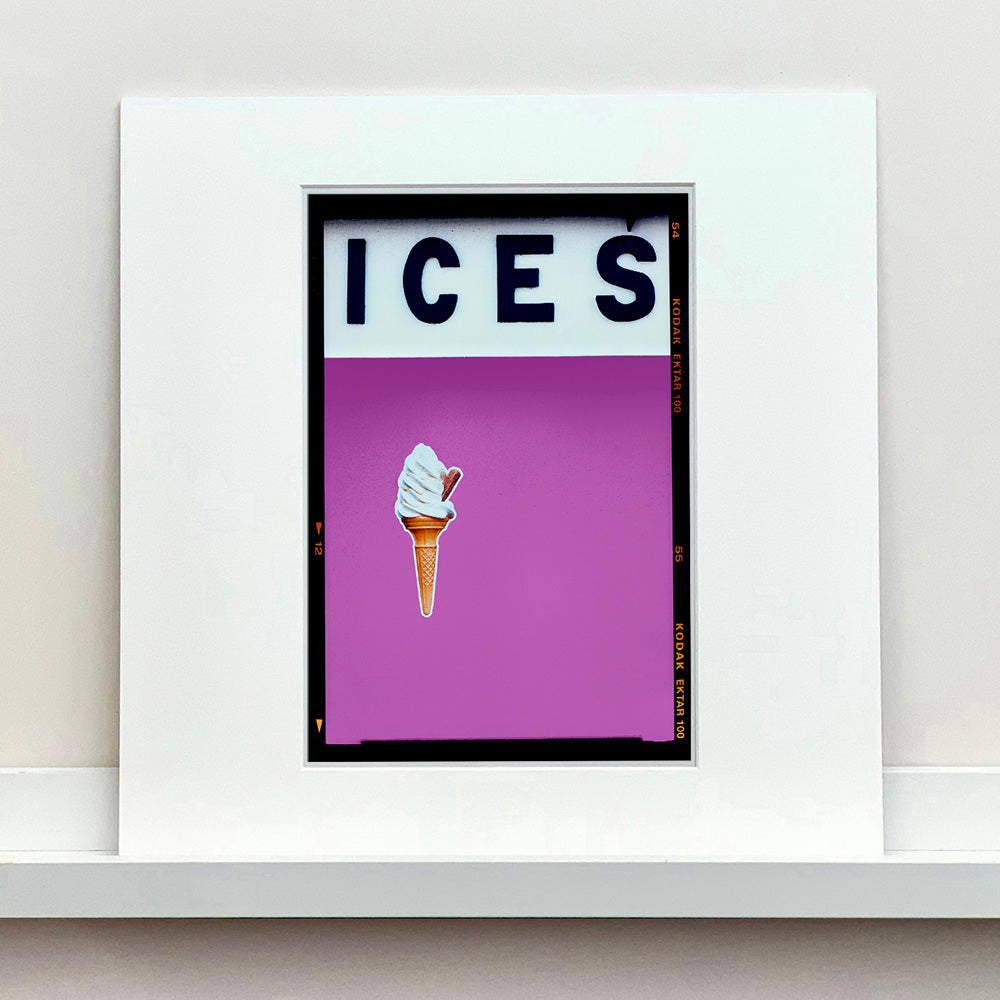 Mounted photograph by Richard Heeps.  At the top black letters spell out ICES and below is depicted a 99 icecream cone sitting left of centre against a plum coloured background.  