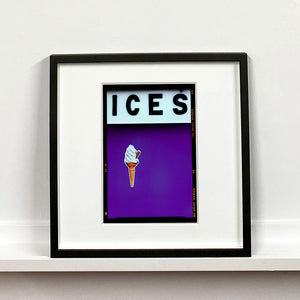 Black framed photograph by Richard Heeps.  At the top black letters spell out ICES and below is depicted a 99 icecream cone sitting left of centre against a purple coloured background.  