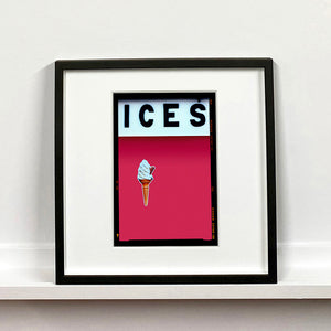 Black framed photograph by Richard Heeps.  At the top black letters spell out ICES and below is depicted a 99 icecream cone sitting left of centre against a raspberry coloured background.  