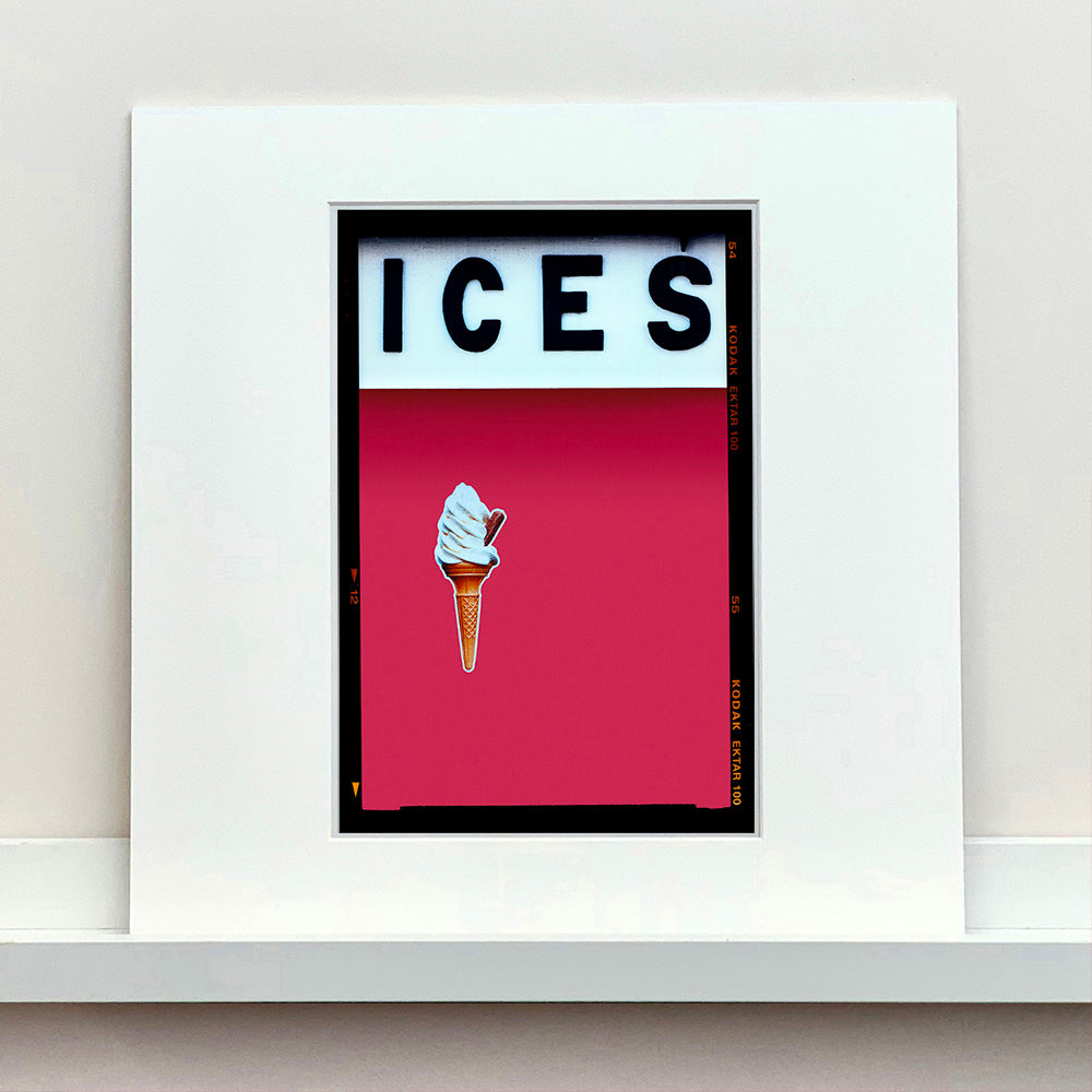 Mounted photograph by Richard Heeps.  At the top black letters spell out ICES and below is depicted a 99 icecream cone sitting left of centre against a raspberry coloured background.  