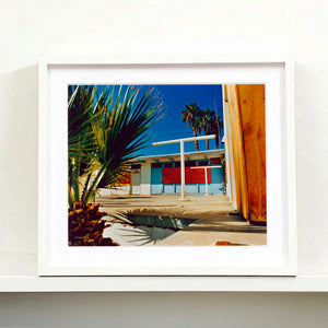 White framed photograph by Richard Heeps. A colourful but derelict vintage motel sits in the blue Californian sun. Palm trees appear behind and to the side. 