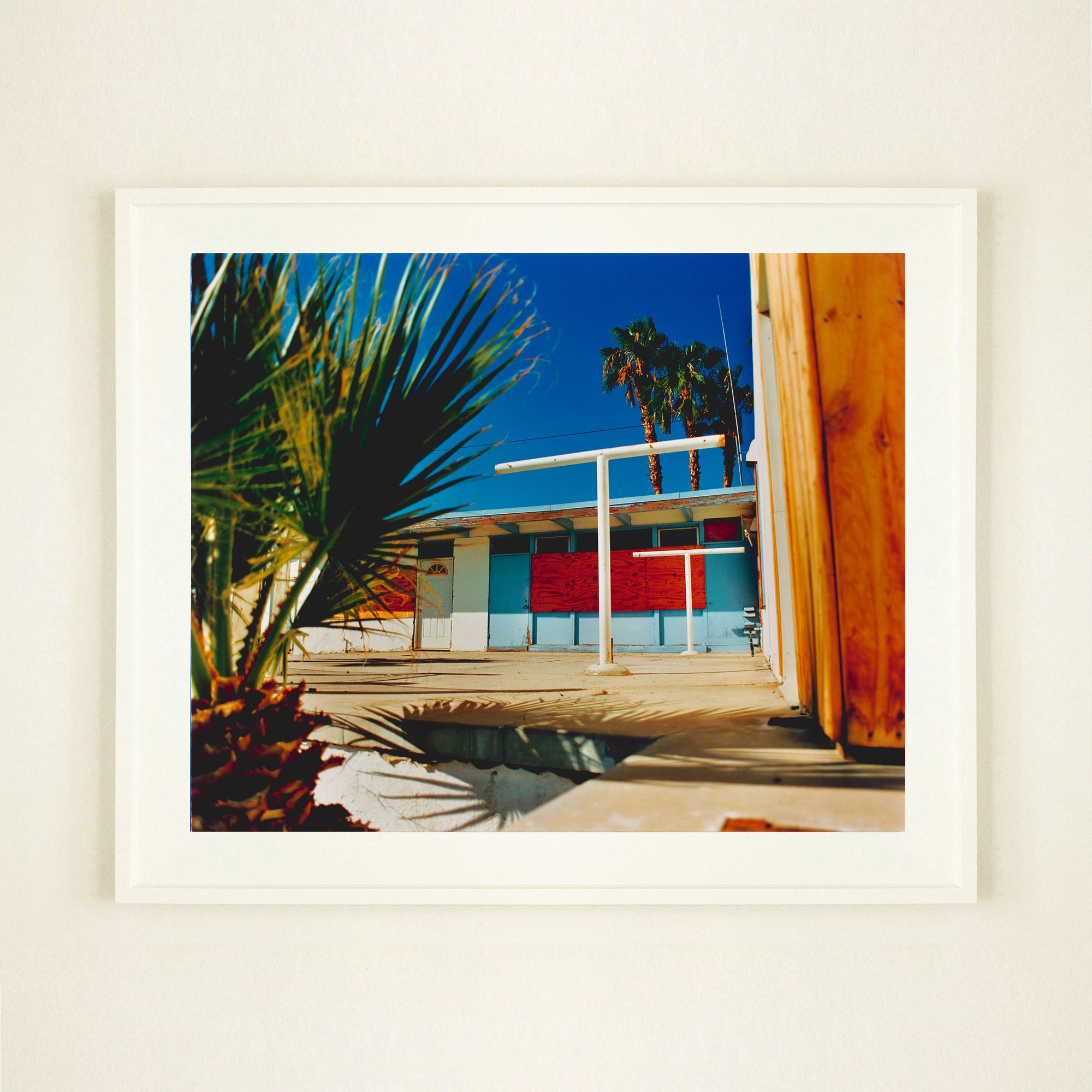 Photograph by Richard Heeps. A colourful but derelict vintage motel sits in the blue Californian sun. Palm trees appear behind and to the side. 
