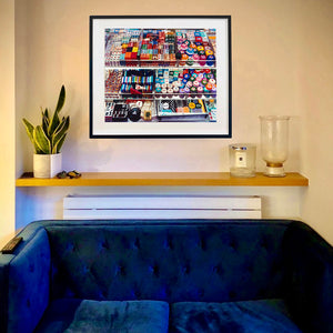 In Situ photograph by Richard Heeps. Three compartmentalised shop shelves, each compartment has coloured plastic dice, counters, circular containers, cards, poker chips, and other plastic type games items.